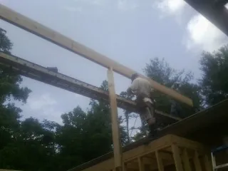 Carpenter setting a ridge beam over a new addition frame — Ice Dam Removal by Roofing Brothers in Reubens