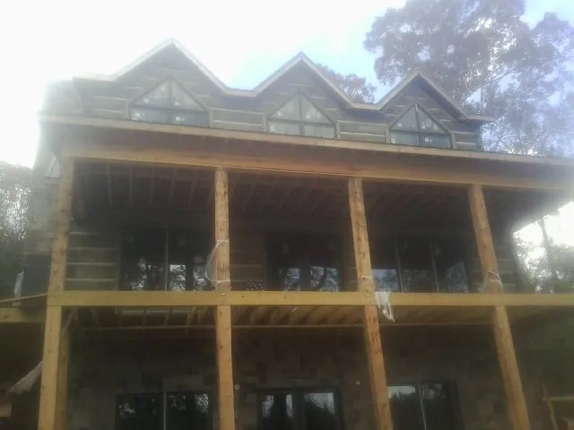 Dormers and porch framing on a large log home under construction — Roof Coating work by our crew in Reubens