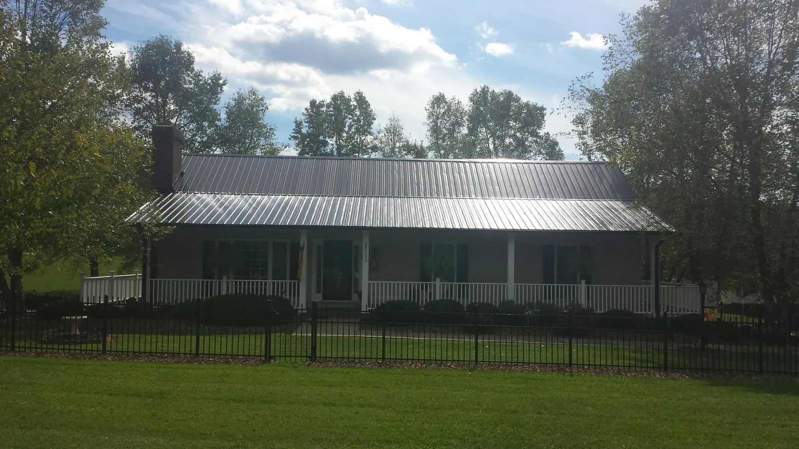 Gray metal roof on a brick ranch with a full width front porch — Gutter Guard Installation work by our crew in Reubens