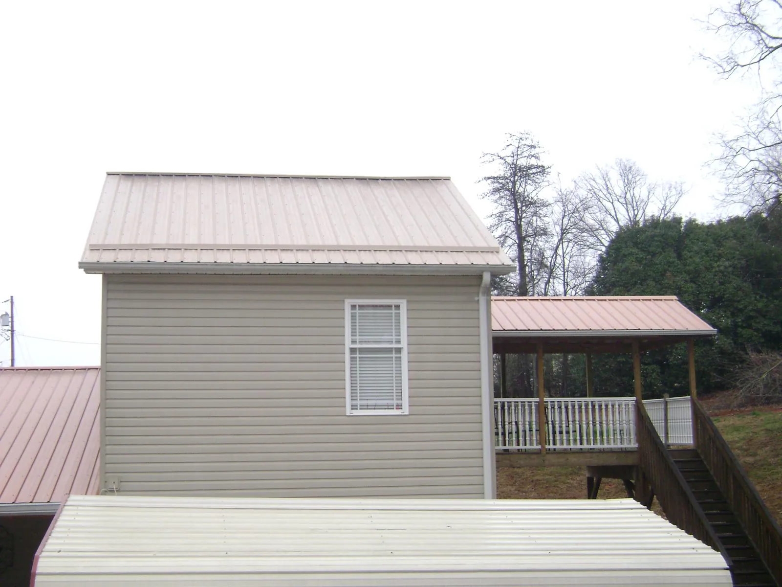 Tan metal roofs on a two story addition and attached porch, from a Roof Replacement job in Reubens