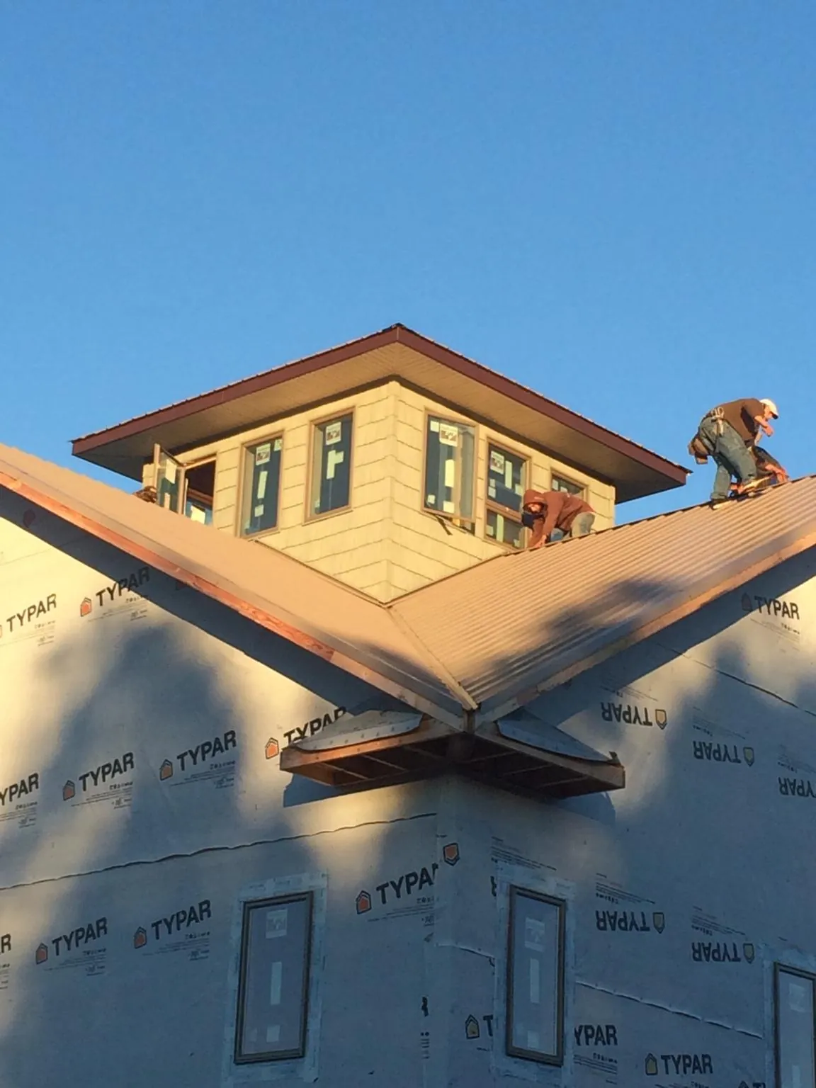 Roofers working around a rooftop cupola on a new metal roof at sunset — Roof Waterproofing in Reubens by Roofing Brothers